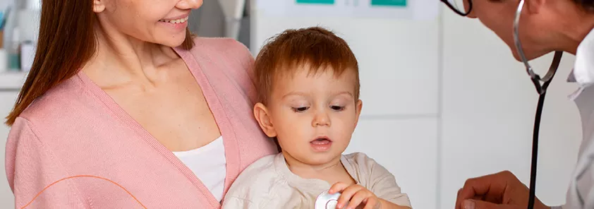 Un bebé con su madre siendo examinado por un doctor