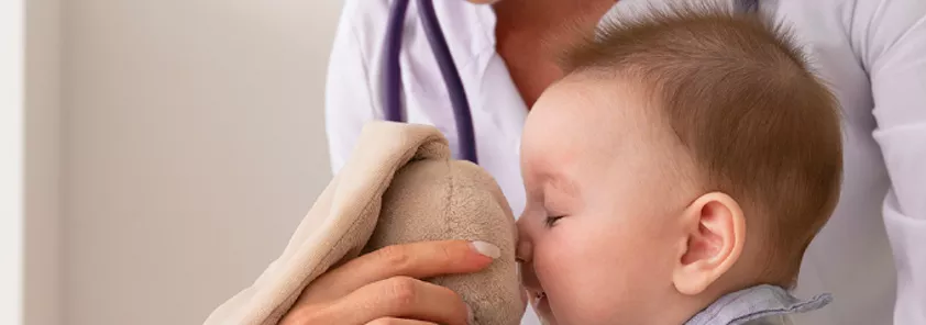 Bebé jugando con un peluche con una doctora