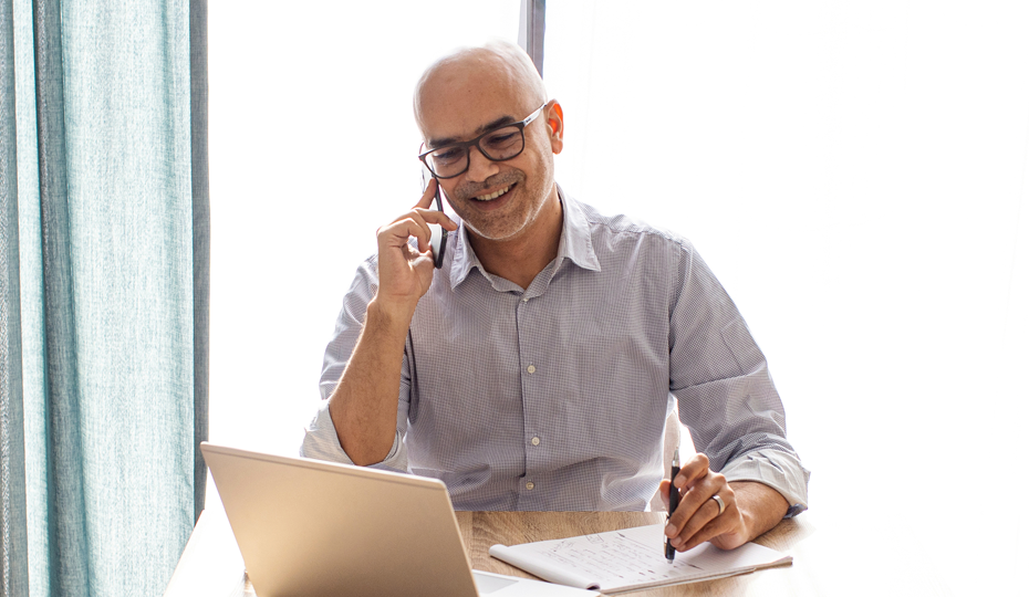 Ein Mann sitzt telefonierend am Tisch