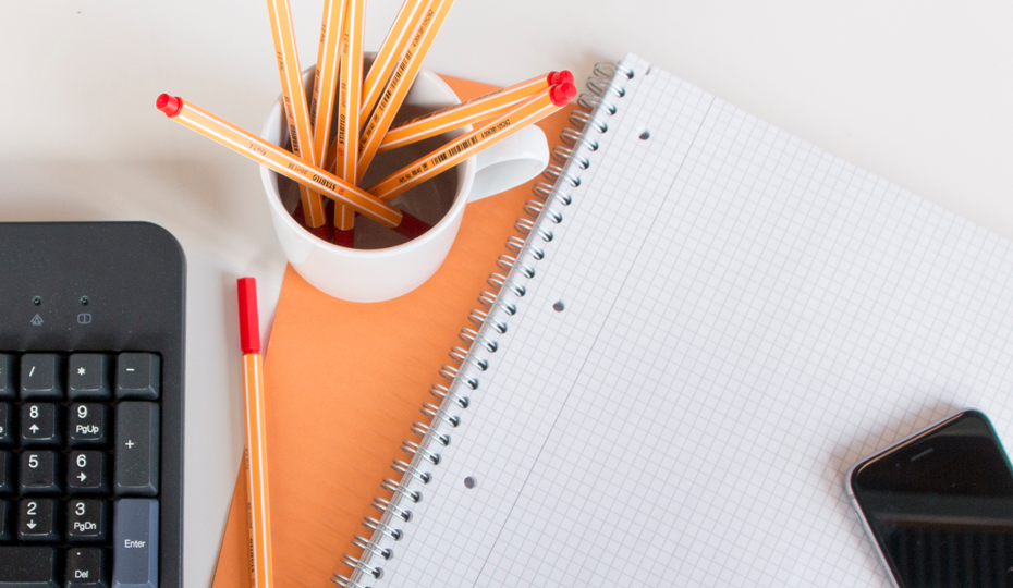 Schreibblock, Stifte, Tastatur und Mobiltelefon