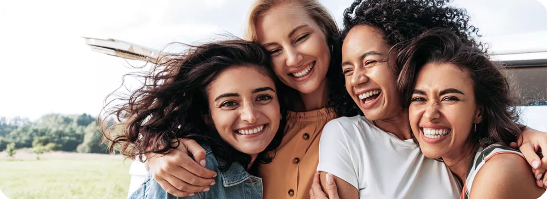 Eine Gruppe von jungen fröhlichen Menschen halten sich im Arm