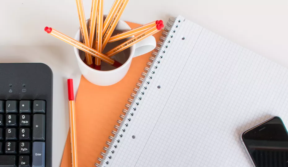 Schreibblock, Stifte, Tastatur und Mobiltelefon